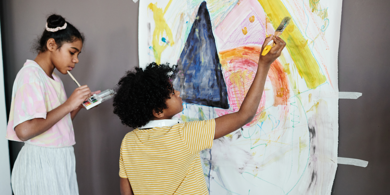 Children painting together on a large canvas.