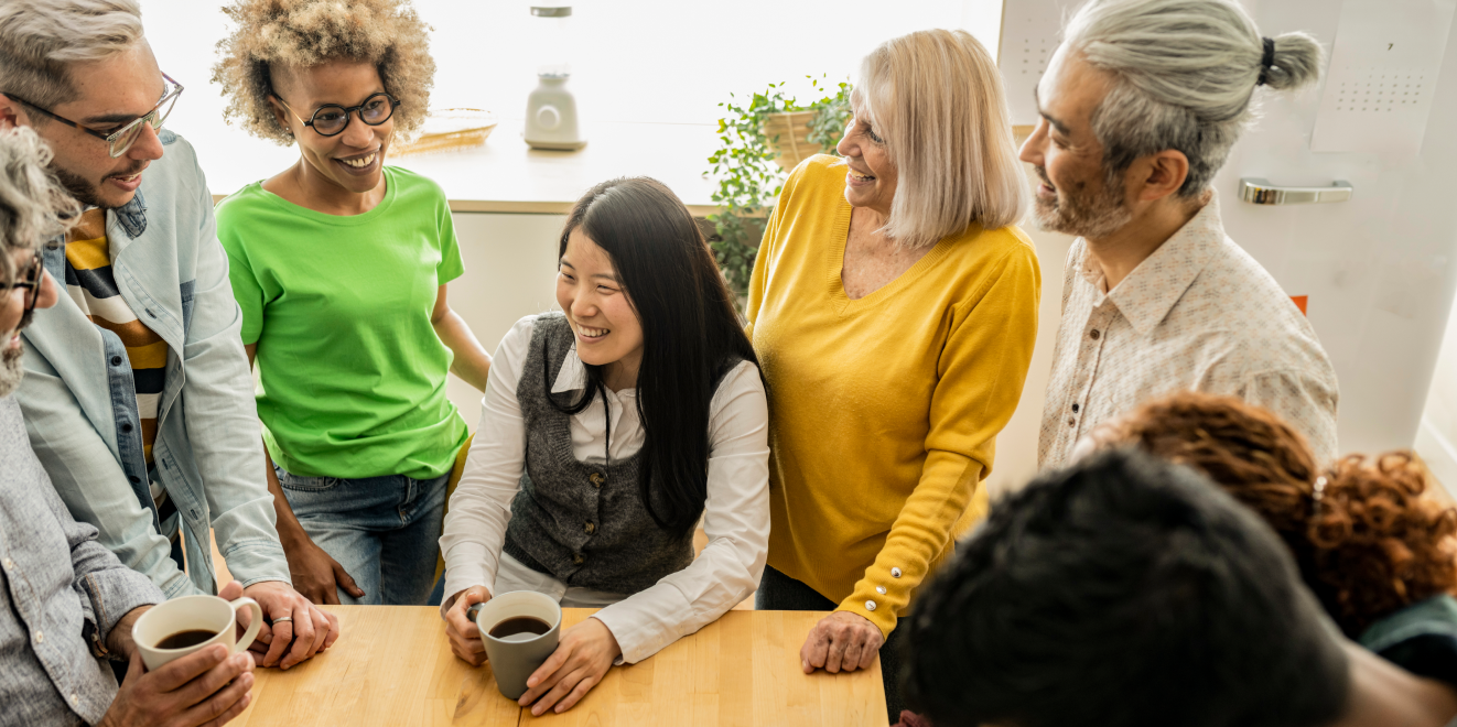 A diverse group of people sitting around a table, engaged in conversation and collaboration.