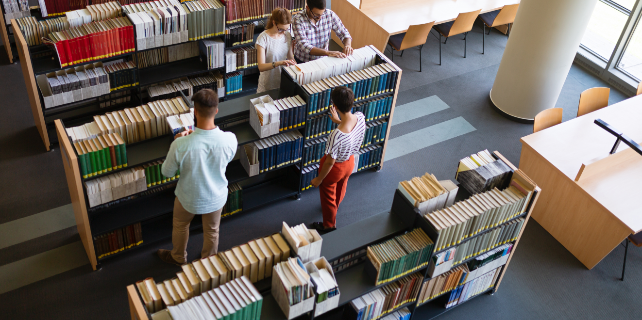 Individuals exploring bookshelves in a library.