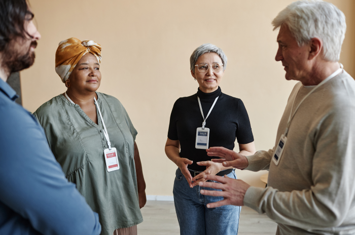 A diverse group of coworkers standing together, having a conversation in the workplace.